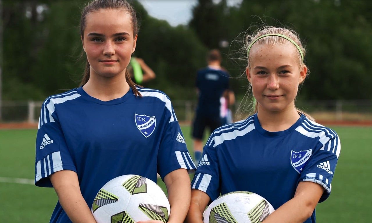 Två flickor håller i var sin fotboll