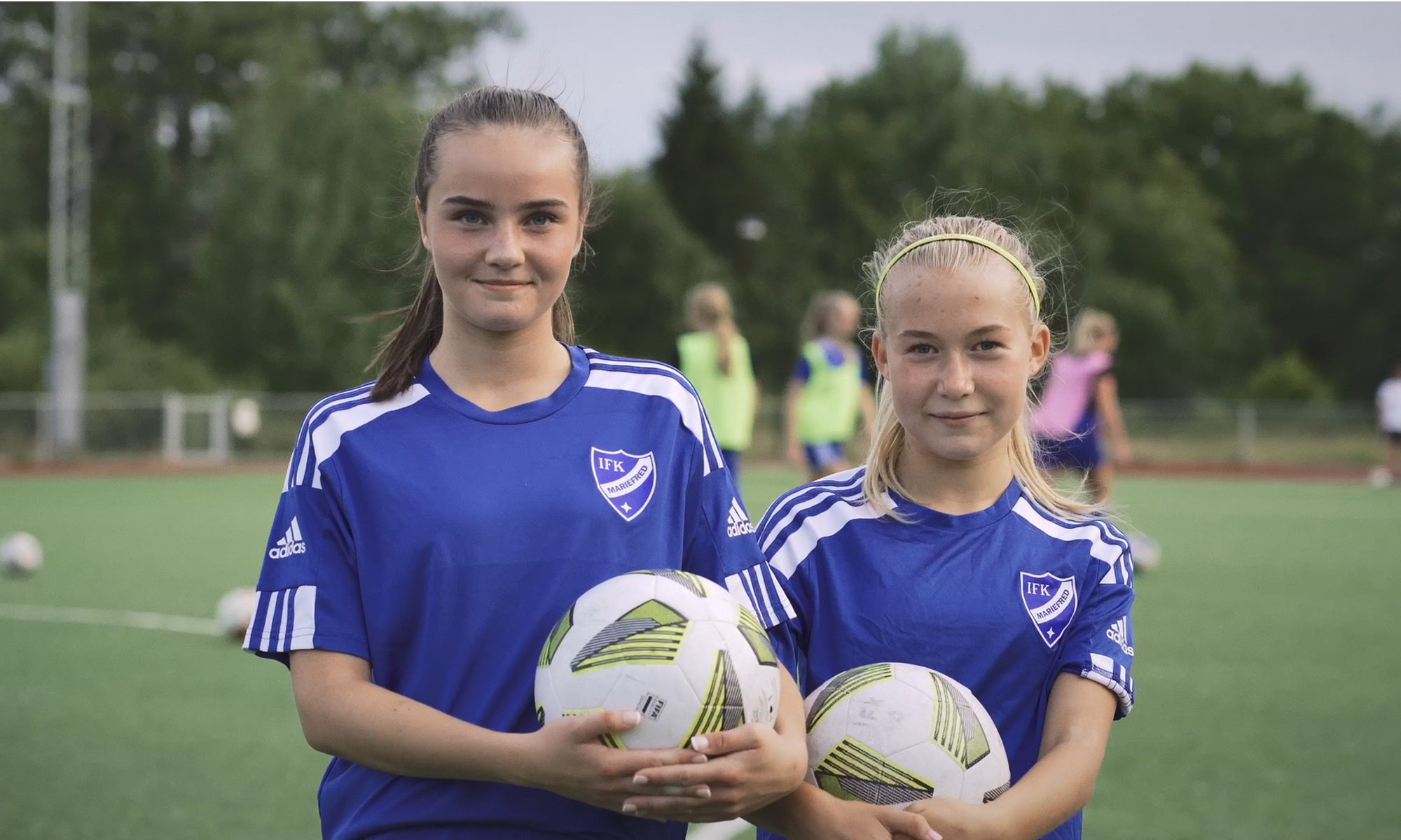 Två flickor håller i var sin fotboll
